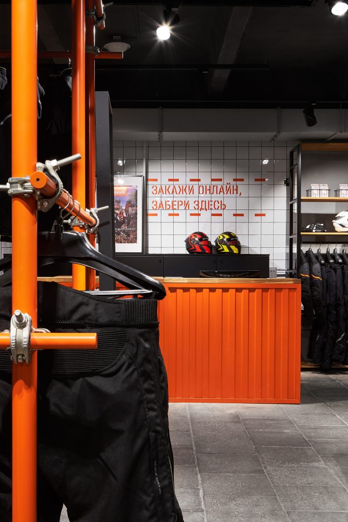 Мотосалон с оранжевым торговым оборудованием на заказ и дизайном маназина в Москве и настенная графика в мотостиле.